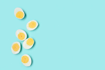 Halves of tasty boiled eggs on blue background