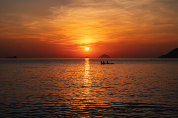 Silhouettes of people floating on sap boards in the sea in the morning at sunrise in summer