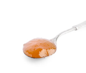 Spoon with sweet apricot jam on white background