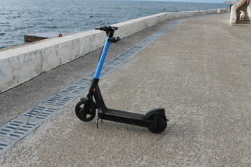 Electric scooter on the road against the background of the sea.