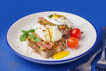 Plate of tasty sandwiches with egg on blue background