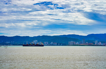 Obraz premium View of container ships, skyline of Georgetown and Penang Hill from the Butterworth ferry boat on the Penang Straits in Georgetown,Penang,Malaysia