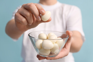 Young woman with glass bowl of fresh boiled quail eggs on blue background