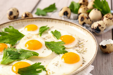 Plate with fried quail eggs and parsley on grey wooden background