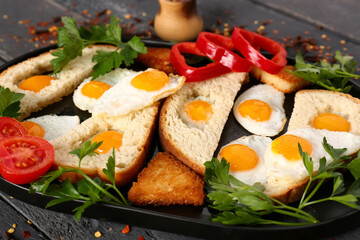 Plate with fried quail eggs, bread, vegetables and parsley on dark wooden table, closeup