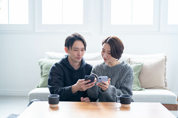 笑顔で携帯を見る日本人カップル
