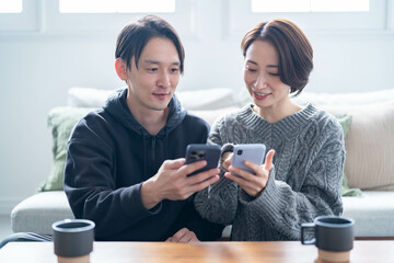 笑顔で携帯を見る日本人カップル