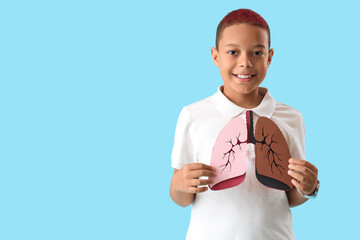 Little African-American boy with paper on blue background