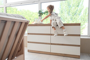 Cute little girl touching candles on high commode at home. Child in danger