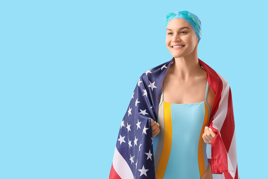 Professional young female swimmer with flag of USA on blue background