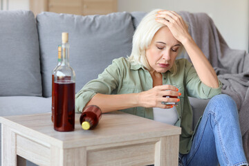 Drunk mature woman at home. Concept of alcoholism