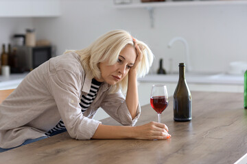 Mature woman drinking wine at home. Concept of alcoholism