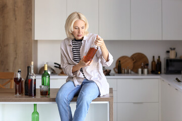 Mature woman with alcohol at home. Concept of alcoholism