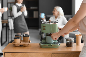 Young woman making coffee in office, closeup