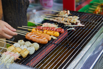 Close-up of hand grill skewer sausage and meatball on barbecue grill
