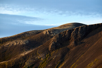 Fototapeta premium Rocky mountain formation with brown cliffs against cloudy blue sky