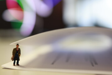 Micro person, business male with suitcase, standing under the page of paper in the office.
