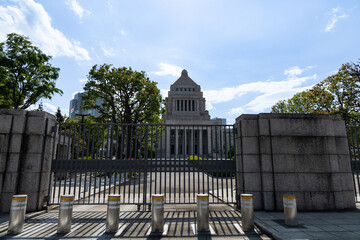 正門の黒い柵越しの日本の国会議事堂と青空
