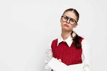 Student looking skeptical with a notebook, wearing glasses and a red sweater, against a plain white background, expressing a thoughtful pose, ideal for educational themes