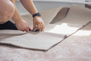 Male hands cutting carpet with blade during apartment renovation. Man in action during apartment...