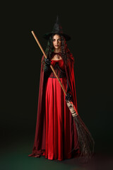 Fototapeta premium Young witch with broom on dark background
