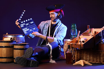 Young pirate with clapperboard on dark background