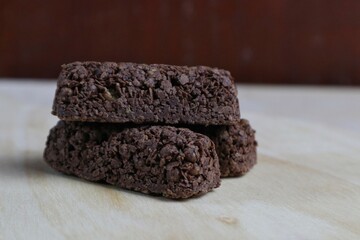 Delicious healthy cereal bar from whole wheat and chocolate with flying crumbs isolated on wooden table background.