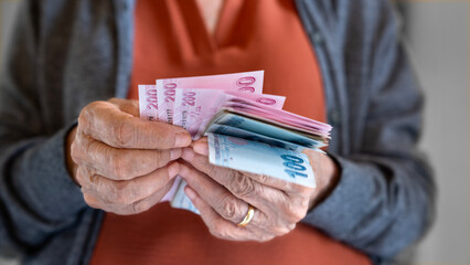 Old woman counting Turkish lira banknotes	
