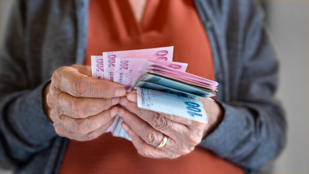 Old woman counting Turkish lira banknotes	