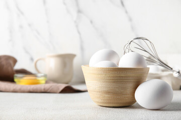 Bowl with raw chicken eggs on white background