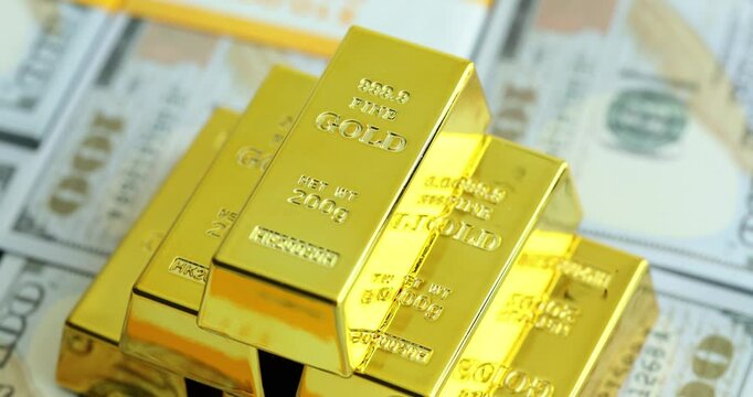Pyramid from gold bars with bank stamps on stacks of dollar bills in light studio. Concept of money investment and accumulation in bank