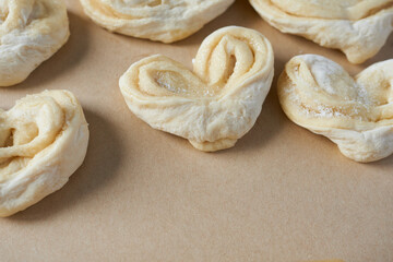 Raw frozen heart-shaped buns on a baking sheet.