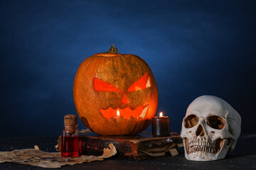Halloween composition with jack-o-lantern, human skull, spell book and bottle of poison on table...
