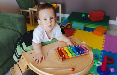 Little boy with neurodevelopmental disorders participates in music therapy using a xylophone,...