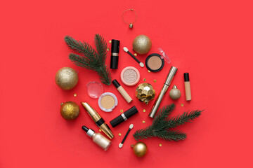 Beautiful Christmas decorations with fir branches and different makeup products on red background