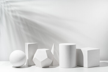 A collection of white geometric shapes arranged on a table in a bright studio setting