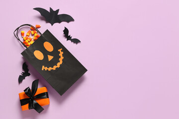 Shopping bag with gift box, Halloween decorations and candies on purple background
