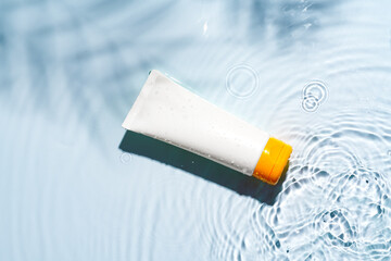 Tropical setting with a skincare tube resting on textured white surface illuminated by sunlight