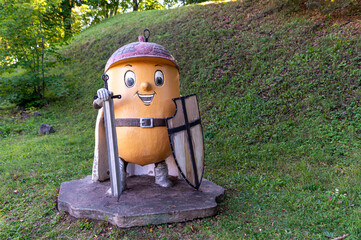 A cheerful statue of the cartoon character oak acorn guards the green park during the day