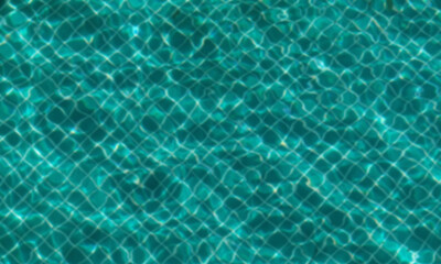 Blurred image of water and tiles in pool. Water waves and reflection in swimming pool