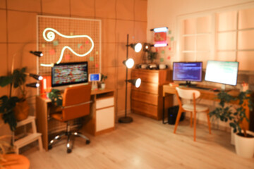 Blurred view of programmer's office with desks and glowing lamps at night