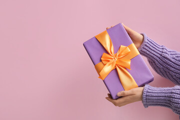 Female hands with Halloween gift on pink background
