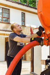 workman connects a suction hose to a sewage tanker truck. Septic tank maintenance. Sewer pumping machine. Septic truck. Pumping wastewater from a septic tank. Septic tank maintenance