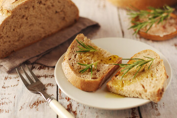 A loaf of rye bread with oil and rosemary in rustic style	