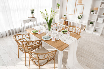 Stylish table setting with vase of Gladiolus flowers near window in kitchen