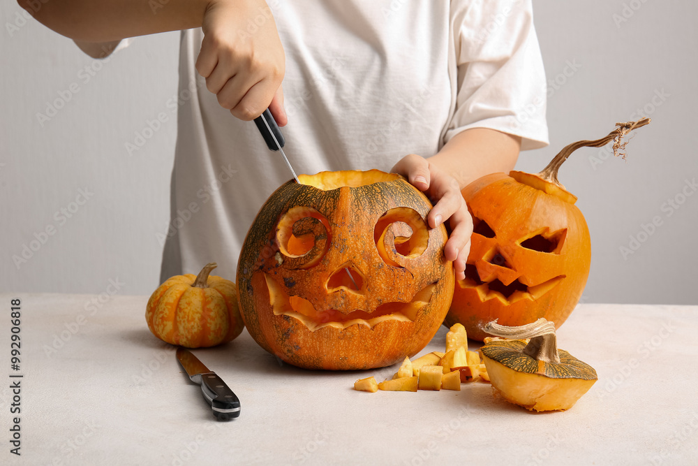 Wall mural Woman with knives carving Jack-O-Lantern pumpkins for Halloween on white background, closeup