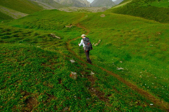 Man hiking through scenic mountains with a backpack on green mountains