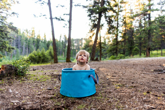 A toddler sits in a bucket while camping in Montana.