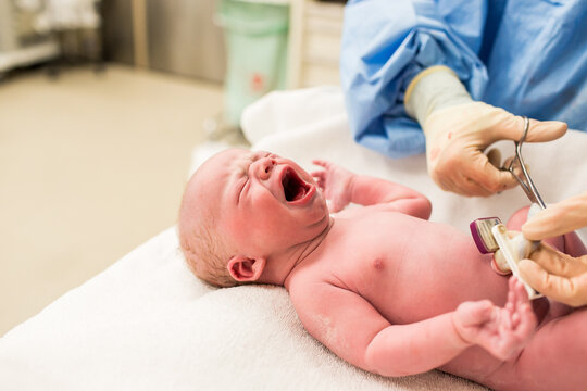 Nurse Cutting Umbilical Cord in Operating Room on Newborn Baby Boy