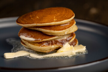 thin hot pancakes with butter on a blue plate